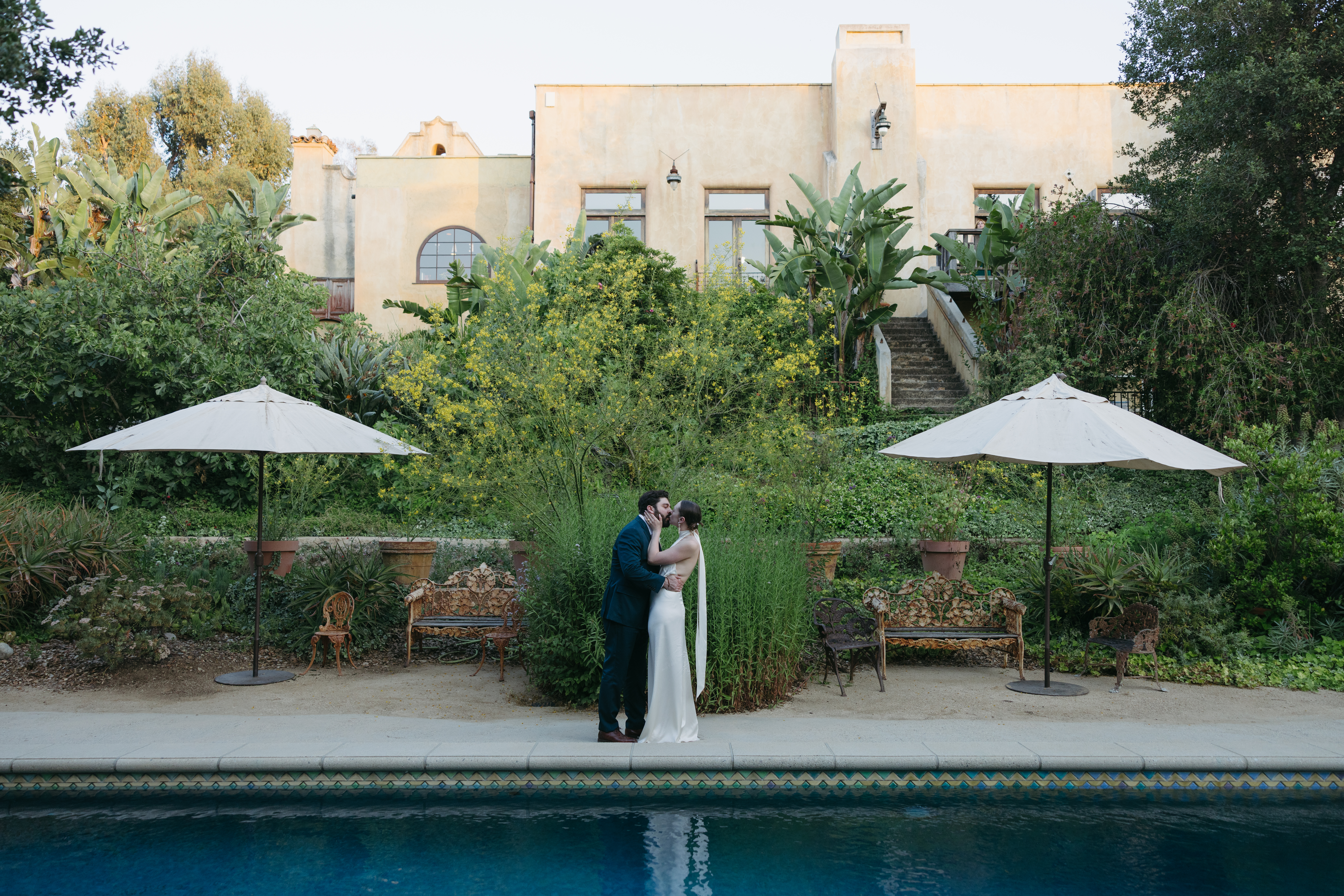 A couple kissing poolside at The Mountain Mermaid wedding venue in Topanga, CA captured by Los Angeles documentary wedding photographer